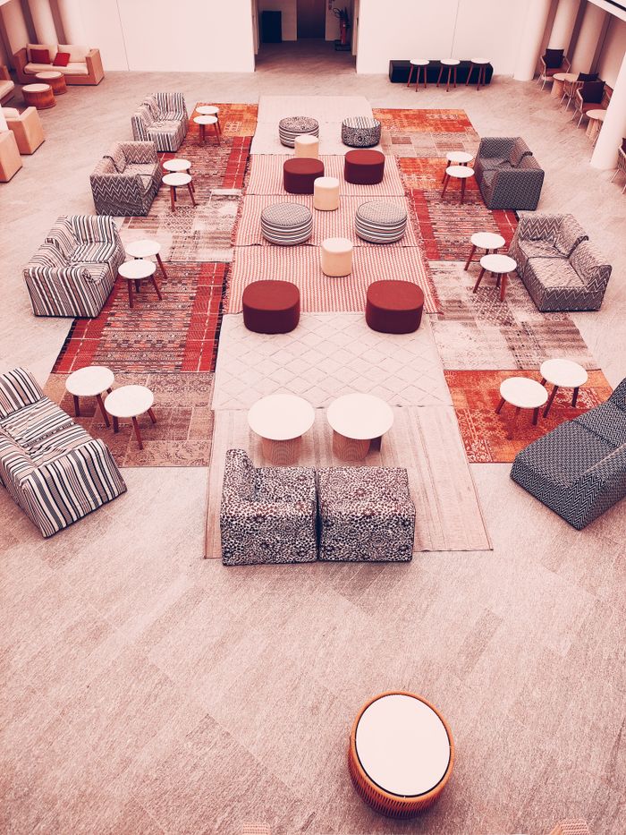 about-us-01 Stylish modern lounge setup with geometric patterns and colorful seating.